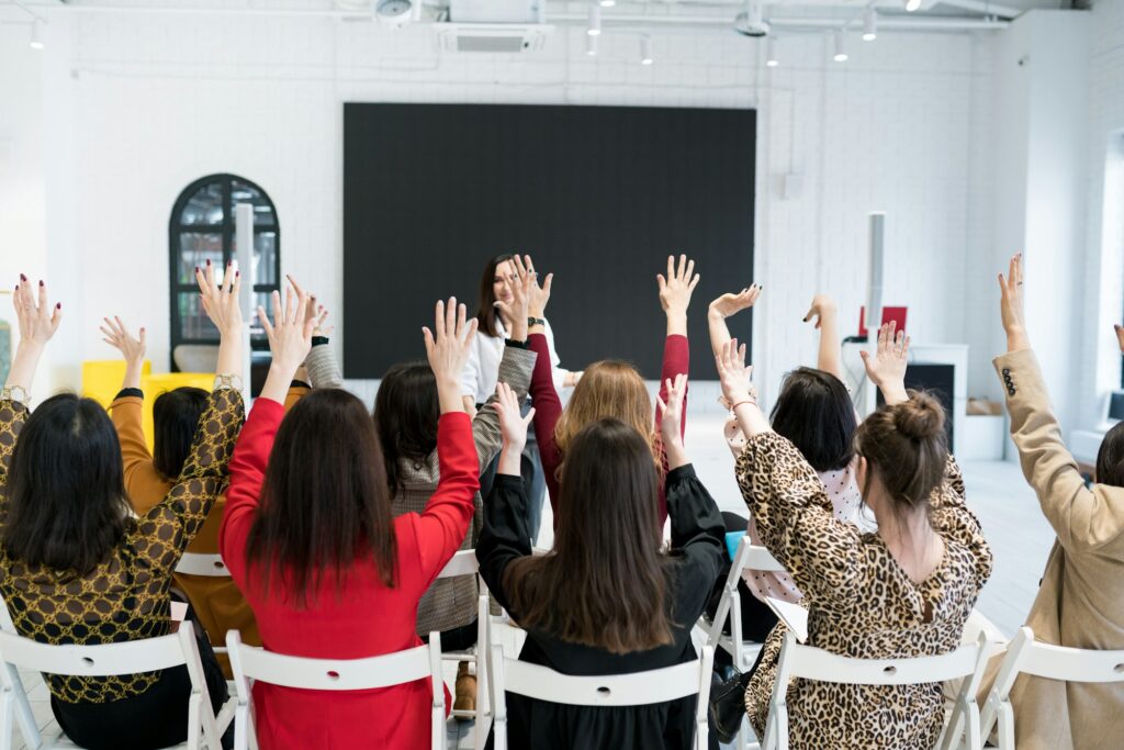 A group of people sitting with their hands up in seminar.