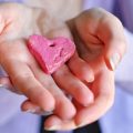 young-woman-holding-a-painted-pink-clay-heart-in-h-2023-11-27-05-26-30-utc